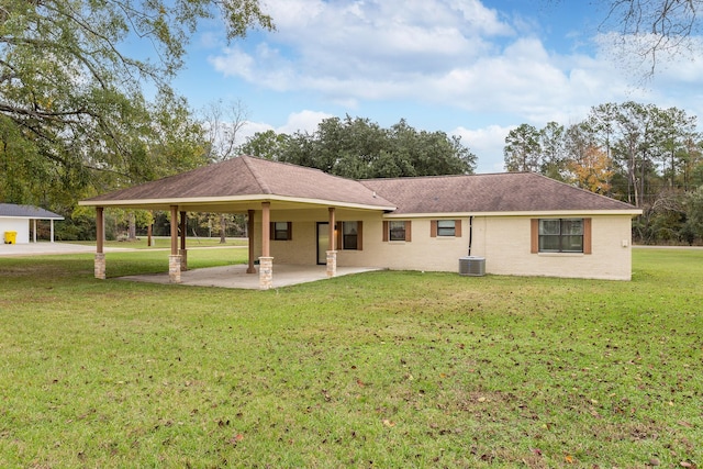 back of house with cooling unit, brick siding, roof with shingles, a lawn, and a patio area