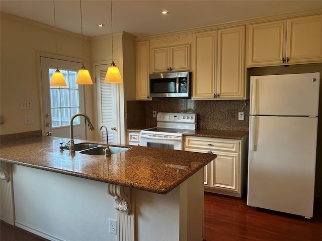 kitchen featuring kitchen peninsula, dark stone counters, white appliances, sink, and decorative light fixtures