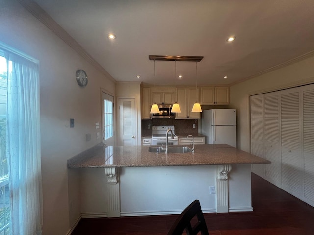 kitchen with appliances with stainless steel finishes, backsplash, light stone counters, sink, and decorative light fixtures