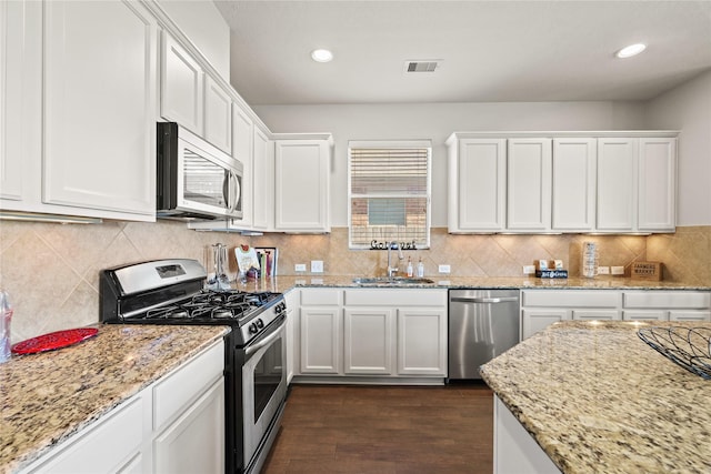 kitchen with appliances with stainless steel finishes, light stone counters, white cabinetry, and sink