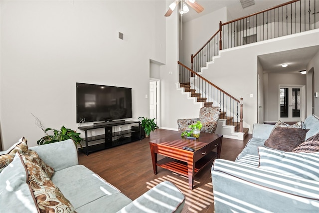 living room with ceiling fan, dark wood-type flooring, and a high ceiling