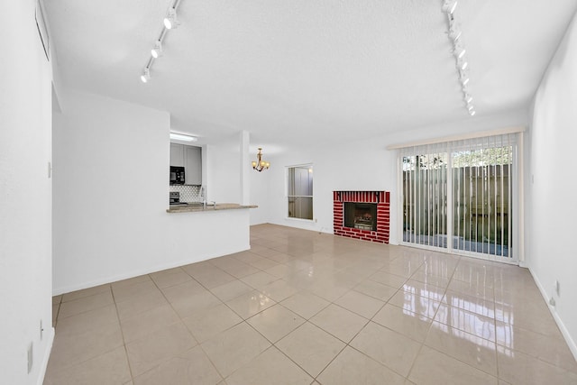 unfurnished living room featuring a fireplace, light tile patterned floors, a chandelier, and sink