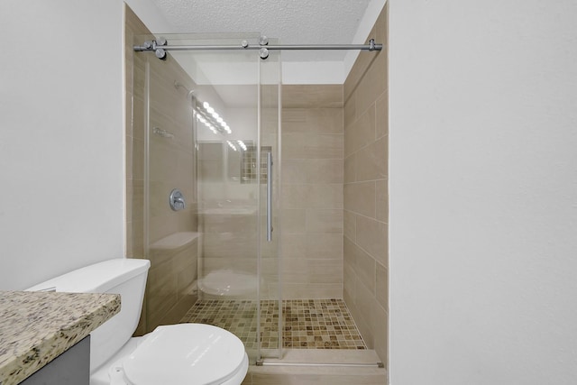 bathroom with toilet, a shower with shower door, and a textured ceiling