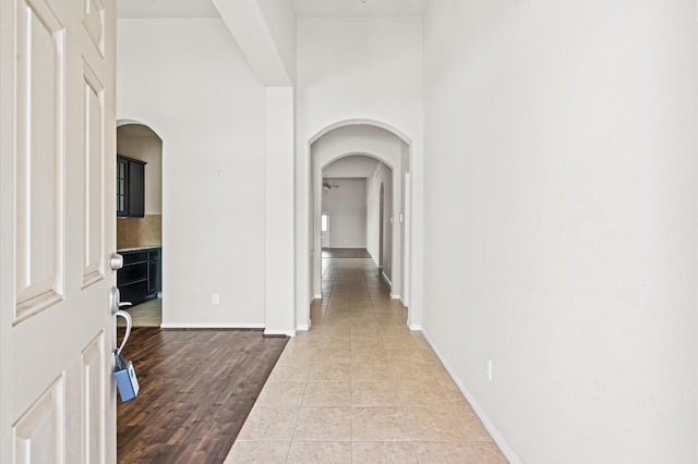 hall featuring light tile patterned floors and a high ceiling