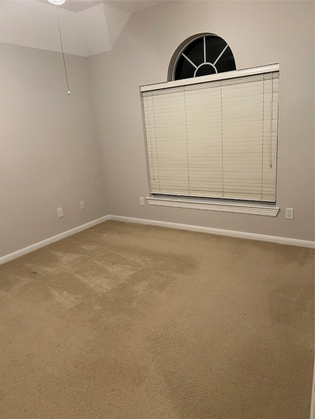 carpeted empty room featuring lofted ceiling