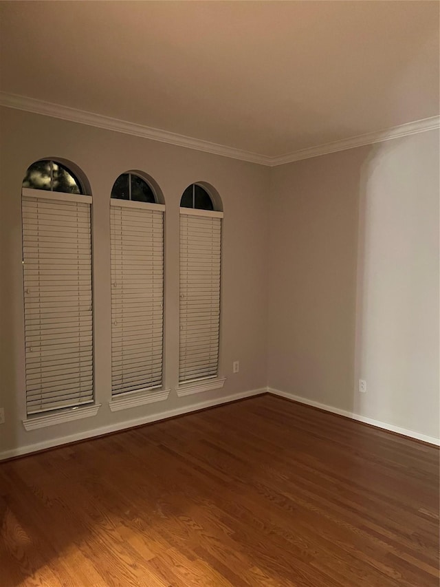 empty room with hardwood / wood-style flooring and crown molding