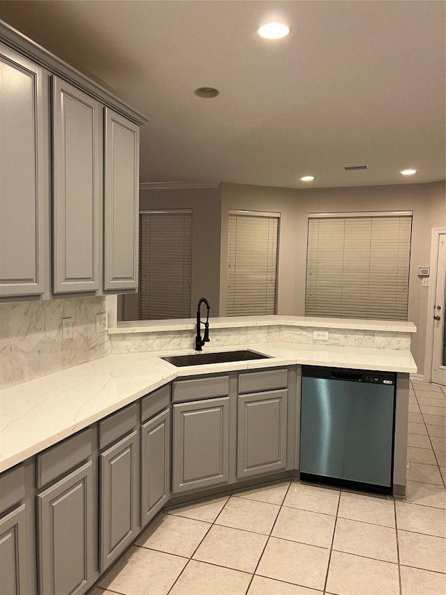 kitchen with tasteful backsplash, gray cabinetry, sink, and stainless steel dishwasher