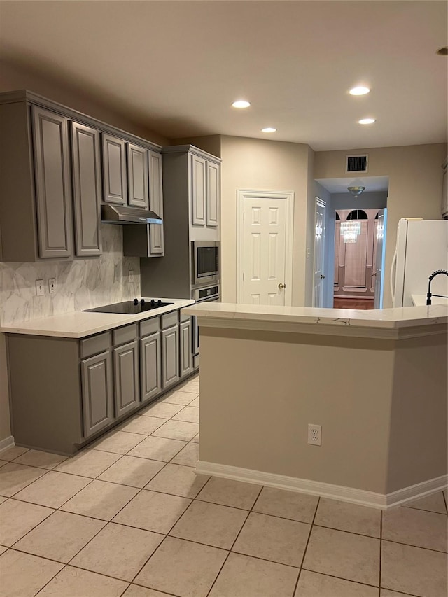 kitchen with appliances with stainless steel finishes, tasteful backsplash, gray cabinetry, and light tile patterned flooring