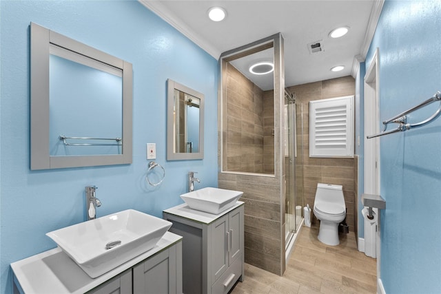 bathroom featuring vanity, toilet, a shower with shower door, and crown molding