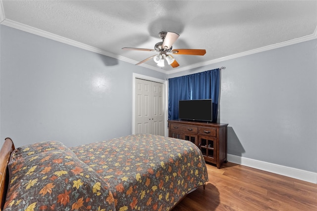 bedroom with ceiling fan, crown molding, hardwood / wood-style floors, a textured ceiling, and a closet