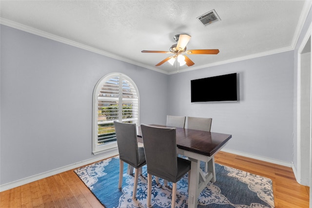 dining area featuring hardwood / wood-style floors, ceiling fan, ornamental molding, and a textured ceiling