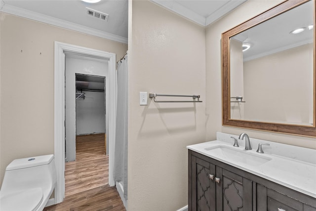 bathroom with vanity, toilet, wood-type flooring, and crown molding