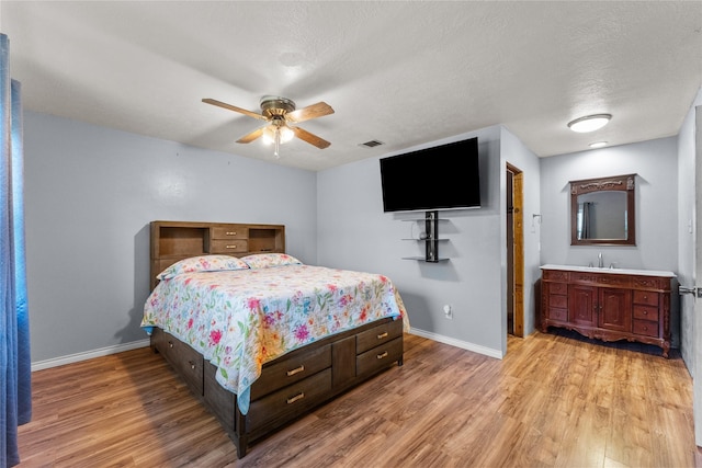 bedroom featuring a textured ceiling, ceiling fan, light hardwood / wood-style floors, and sink