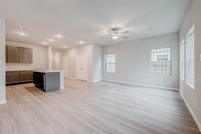 kitchen with sink, a center island with sink, ceiling fan, and light hardwood / wood-style floors