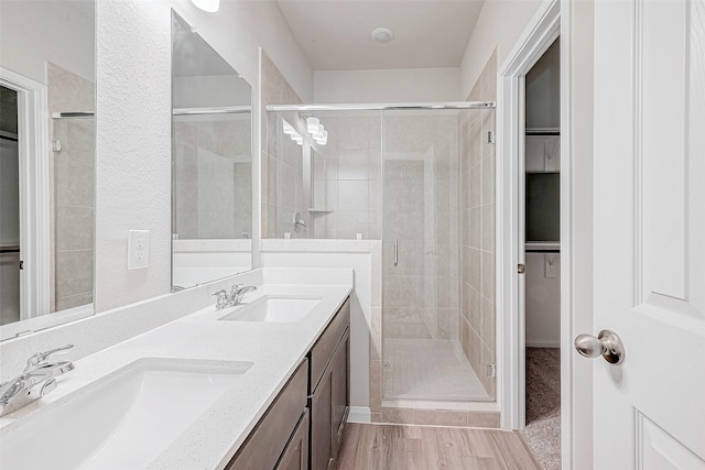 bathroom featuring hardwood / wood-style flooring, a shower with door, and vanity