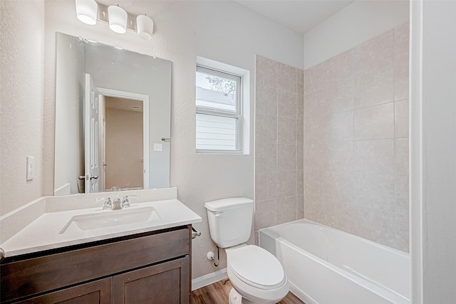 full bathroom with hardwood / wood-style floors, tiled shower / bath combo, vanity, and toilet