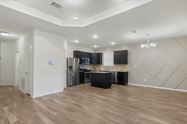 kitchen featuring tasteful backsplash, a notable chandelier, light hardwood / wood-style floors, a kitchen island, and stainless steel appliances