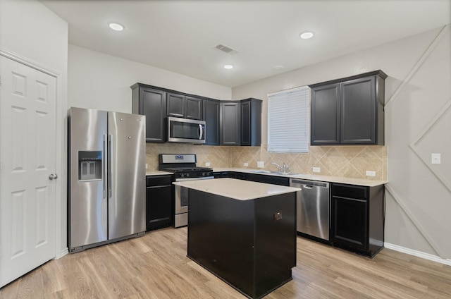 kitchen featuring light hardwood / wood-style floors, stainless steel appliances, decorative backsplash, a center island, and sink