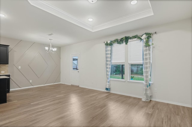 unfurnished living room with wood-type flooring, a tray ceiling, and a notable chandelier