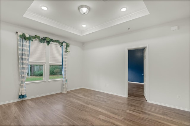 empty room with crown molding, hardwood / wood-style floors, and a tray ceiling