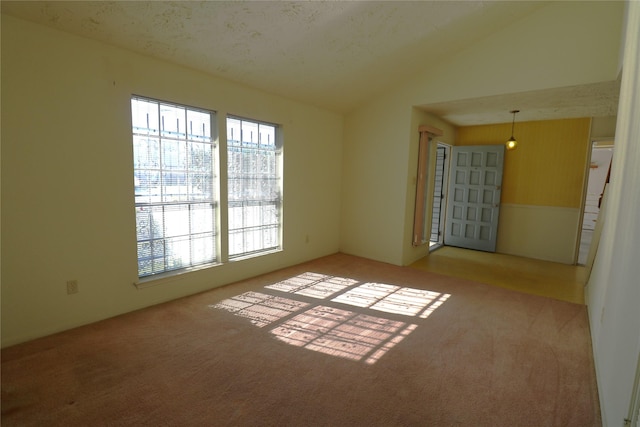 carpeted spare room featuring a textured ceiling and vaulted ceiling