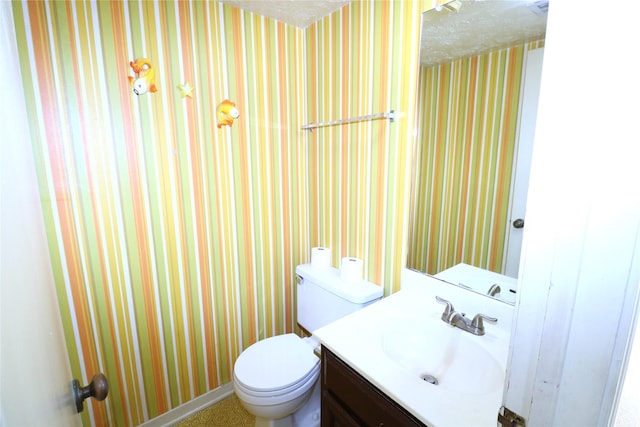 bathroom with vanity, toilet, and a textured ceiling