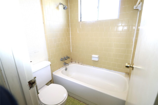 bathroom with toilet and tiled shower / bath