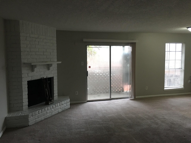 unfurnished living room with a textured ceiling, carpet floors, a brick fireplace, and a healthy amount of sunlight