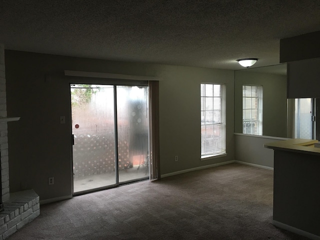 unfurnished living room featuring carpet flooring, a fireplace, a healthy amount of sunlight, and a textured ceiling