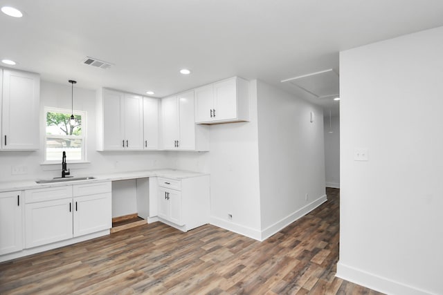 kitchen with white cabinets, hanging light fixtures, dark wood-type flooring, and sink