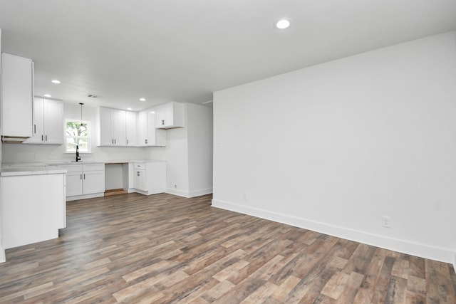 kitchen with dark hardwood / wood-style flooring, sink, white cabinets, and hanging light fixtures