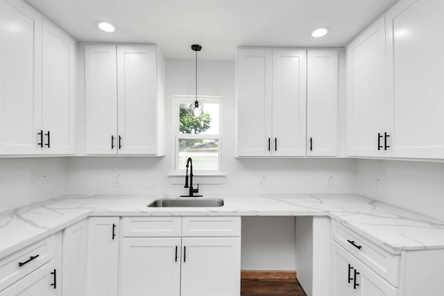 kitchen featuring dark wood-type flooring, sink, light stone countertops, decorative light fixtures, and white cabinetry