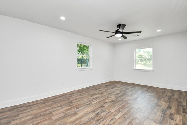 spare room featuring plenty of natural light, ceiling fan, and dark wood-type flooring