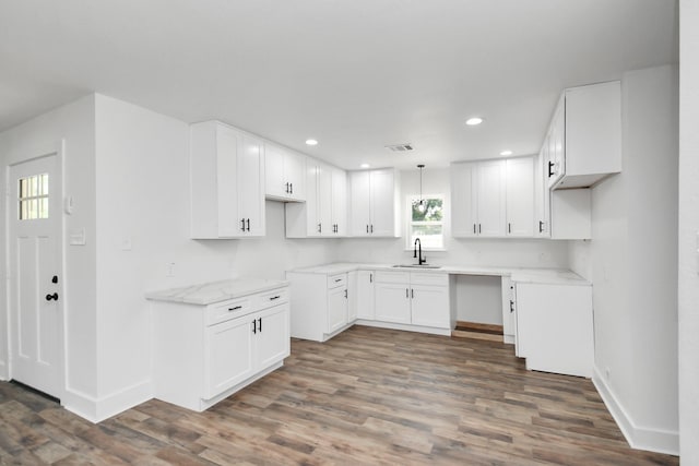 kitchen with dark hardwood / wood-style flooring, light stone counters, white cabinetry, and sink