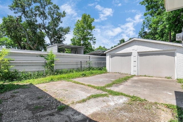 view of yard featuring an outbuilding, a carport, and a garage