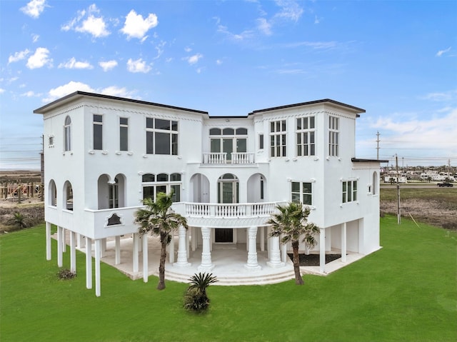 back of house featuring a balcony, a patio area, and a lawn