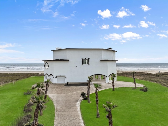 view of outbuilding with a water view, a view of the beach, and decorative driveway