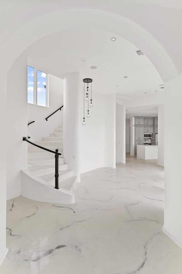 interior space featuring arched walkways, marble finish floor, stairway, and visible vents