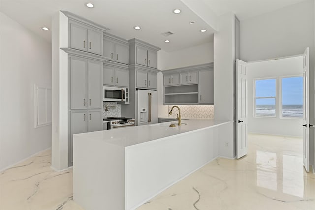 kitchen featuring marble finish floor, tasteful backsplash, light countertops, a sink, and white appliances