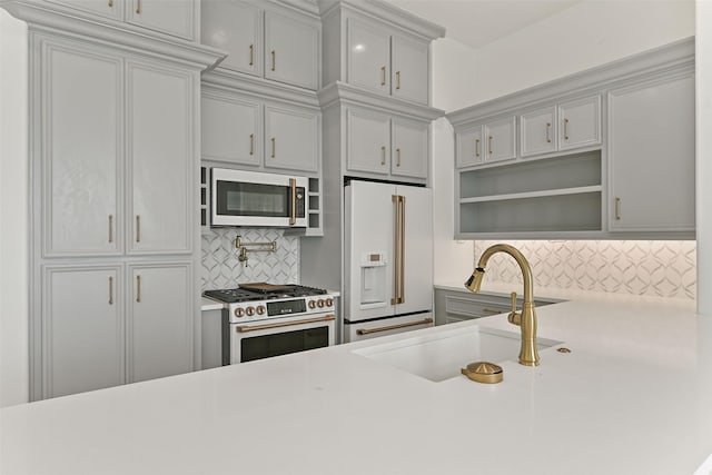 kitchen featuring open shelves, high quality appliances, light countertops, and a sink