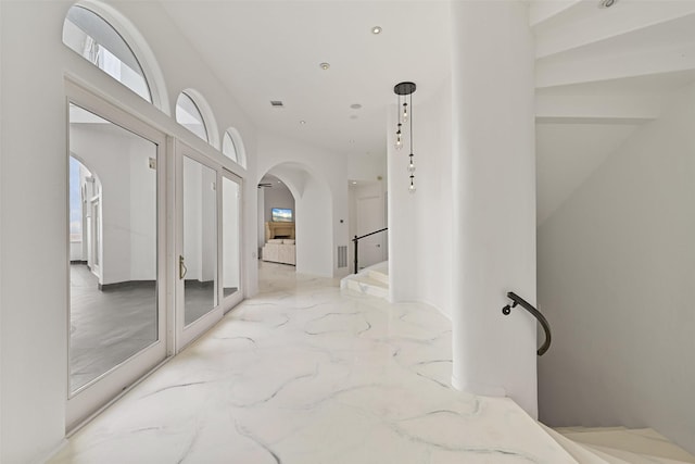 hall with marble finish floor, visible vents, arched walkways, and recessed lighting