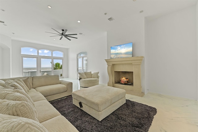 carpeted living area featuring ceiling fan, a fireplace with flush hearth, visible vents, and recessed lighting