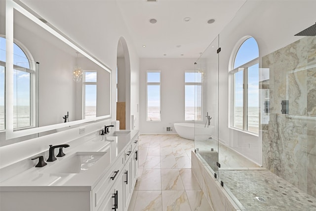 full bath with marble finish floor, a sink, a freestanding tub, and a marble finish shower