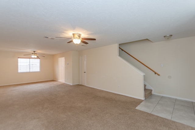 empty room featuring ceiling fan, light colored carpet, and a textured ceiling