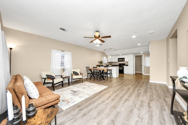 living room with light wood-type flooring and ceiling fan