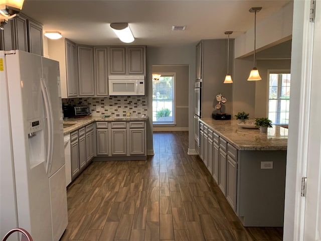 kitchen with light stone counters, white appliances, decorative backsplash, and pendant lighting