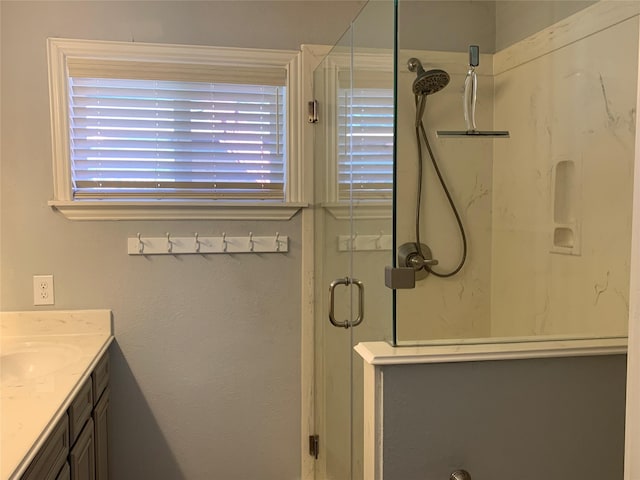 bathroom featuring a shower with door and vanity