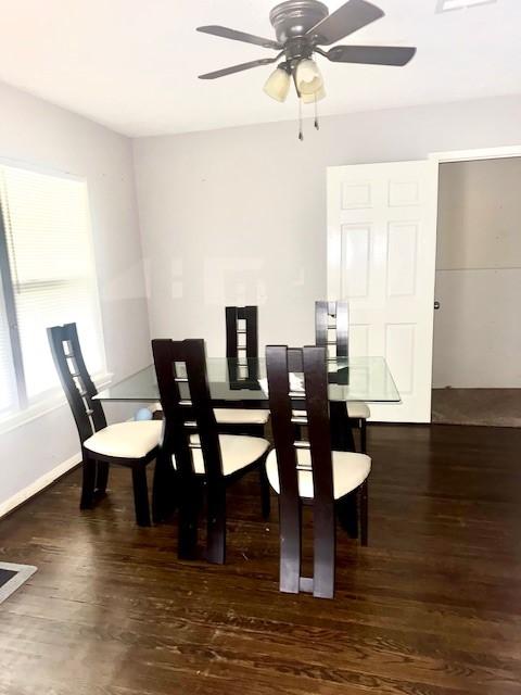 dining space with ceiling fan and dark wood-type flooring