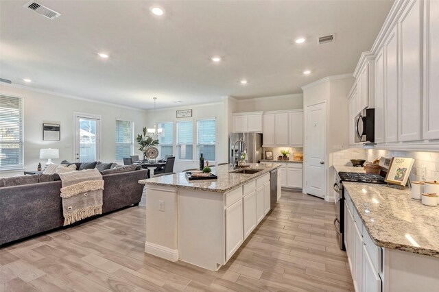 kitchen with stainless steel appliances, sink, white cabinets, and a kitchen island with sink