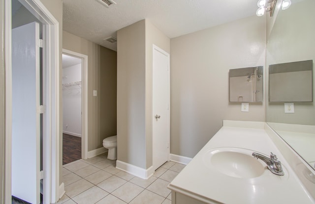 bathroom featuring tile patterned flooring, vanity, toilet, and a textured ceiling